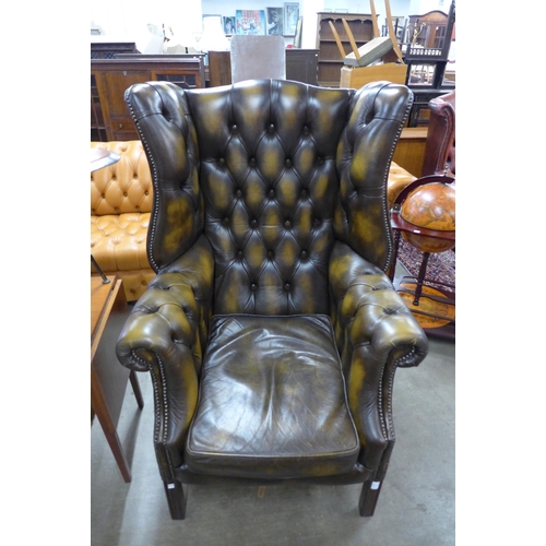 7 - A mahogany and chestnut brown leather Chesterfield wingback armchair