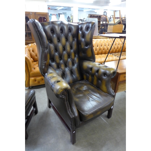 8 - A mahogany and chestnut brown leather Chesterfield wingback armchair