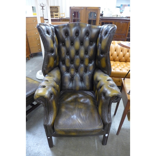 8 - A mahogany and chestnut brown leather Chesterfield wingback armchair