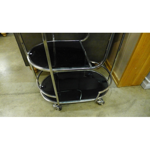 1360 - A pill shaped metal drinks trolley with black glass shelves  *This lot is subject to VAT