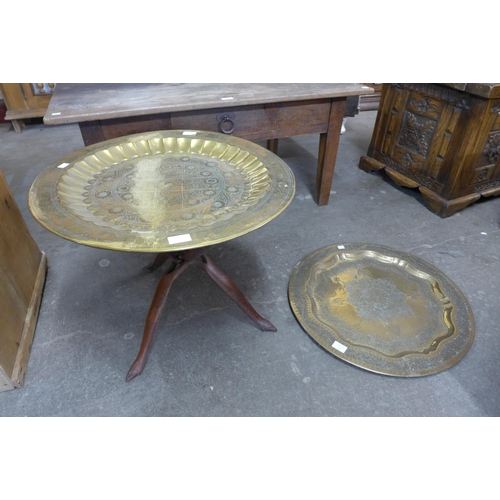 135 - An eastern brass topped folding occasional table and another brass charger