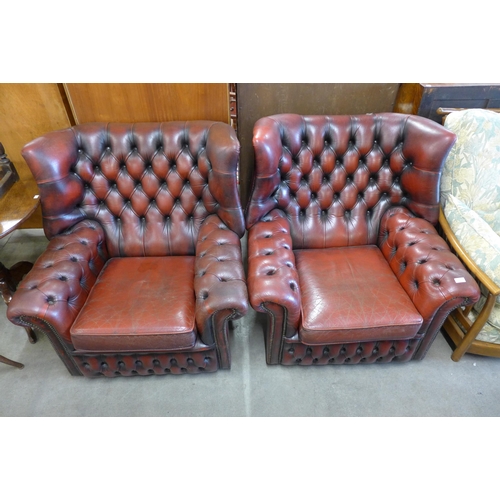 170 - A pair of oxblood red leather Chesterfield wingback armchairs