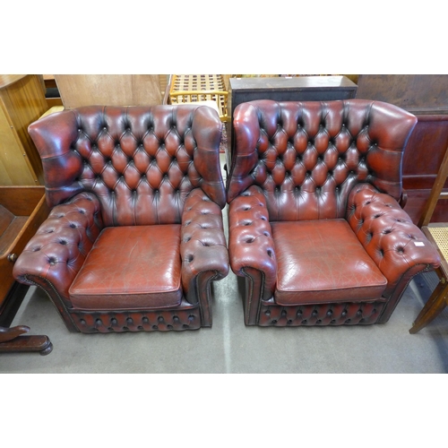 217 - A pair of oxblood red leather Chesterfield wingback armchairs