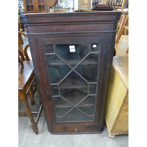 251 - A George III oak splay front wall hanging corner cupboard