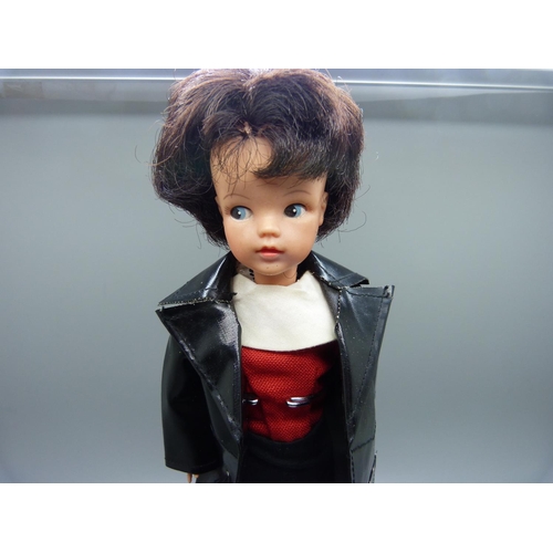 832 - A 1960's Sindy in black plastic coat with shoes, on stand