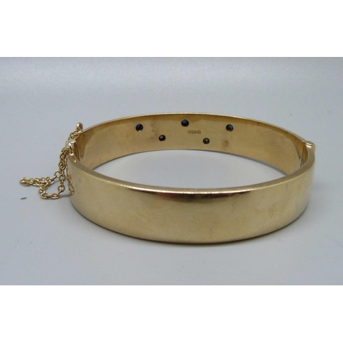 826 - A 9ct gold, sapphire and diamond bangle, 24.7g, marked 'wax filled', inner measurement 55mm x 62mm, ... 