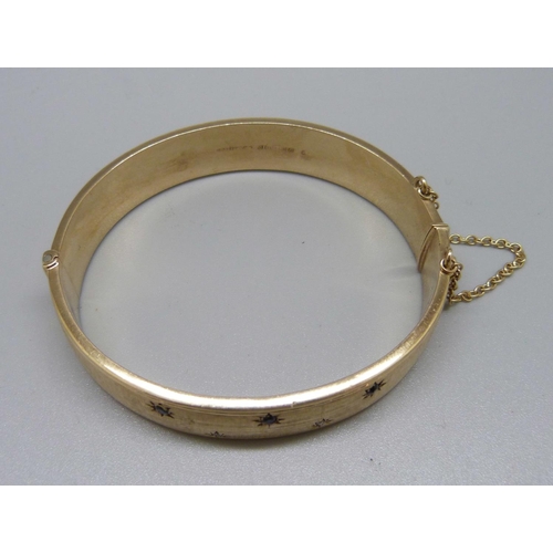 826 - A 9ct gold, sapphire and diamond bangle, 24.7g, marked 'wax filled', inner measurement 55mm x 62mm, ... 