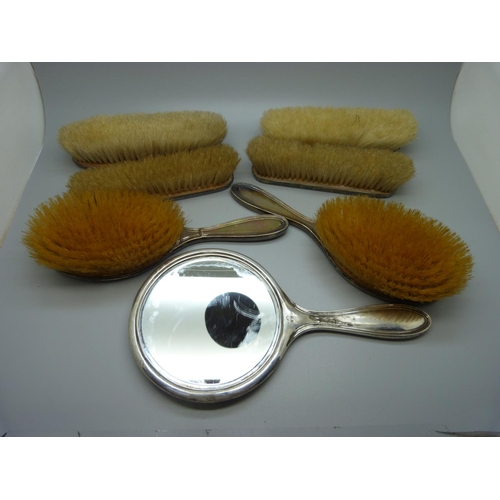 847 - Six silver backed brushes and a hand mirror