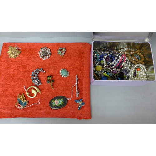 666 - Eleven costume brooches and a tin of costume jewellery