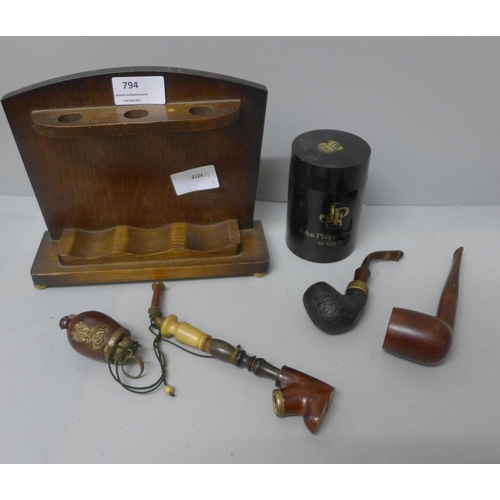 794 - A wooden smokers stand with three pipes, and a John Players plastic tobacco container