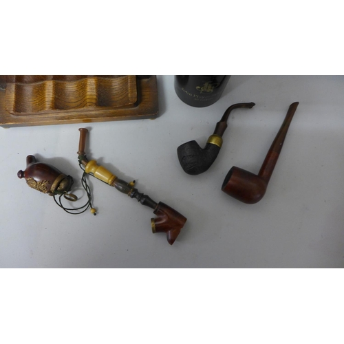 794 - A wooden smokers stand with three pipes, and a John Players plastic tobacco container