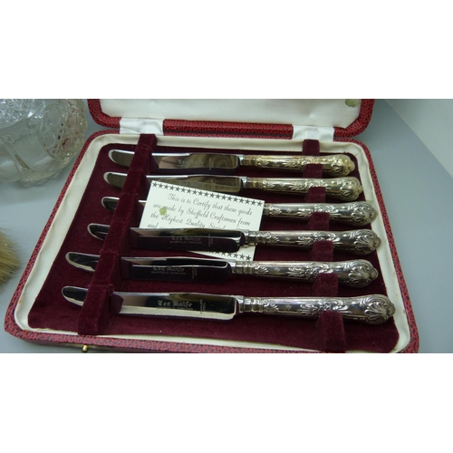 857 - A cased set of silver handled knives, two silver backed brushes, and a silver topped glass scent bot... 