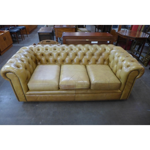 87 - A tan leather Chesterfield settee