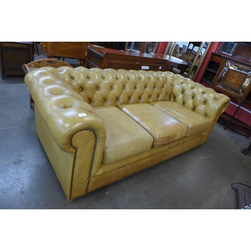 87 - A tan leather Chesterfield settee