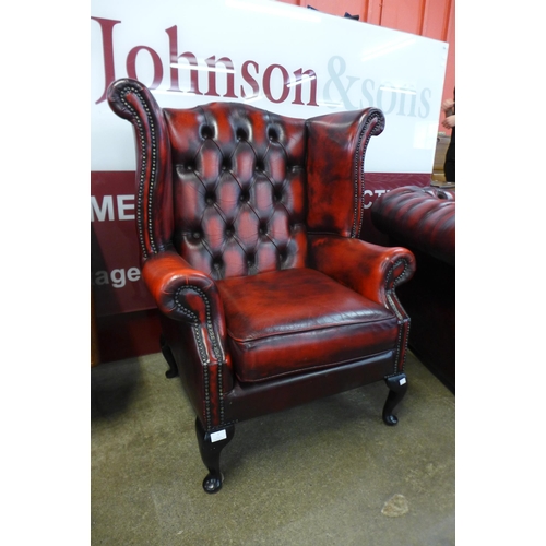 1 - A mahogany and red leather Chesterfield wingback armchair