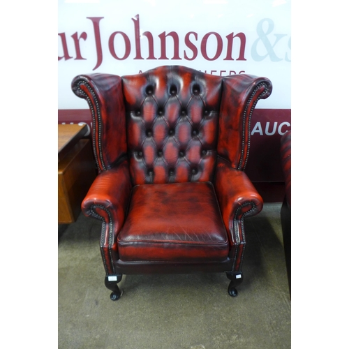 1 - A mahogany and red leather Chesterfield wingback armchair