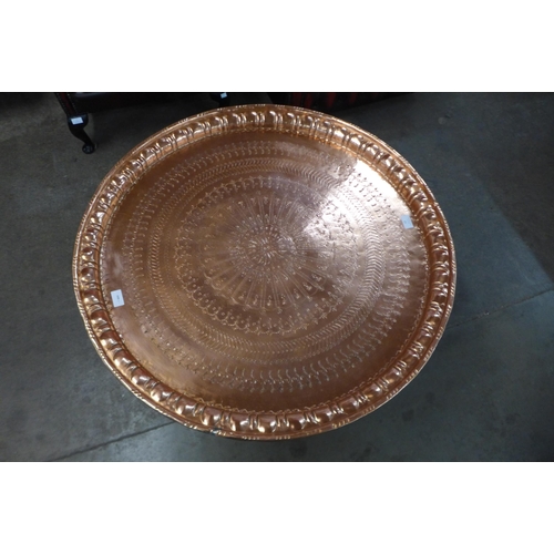 13 - An Egyptian copper coffee table, on carved hardwood folding base