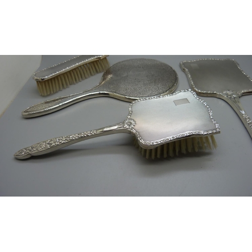 852 - A silver backed hand mirror with two matching brushes, one other silver backed hand mirror and a sil... 