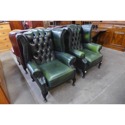 25 - A green leather Chesterfield wingback armchairs