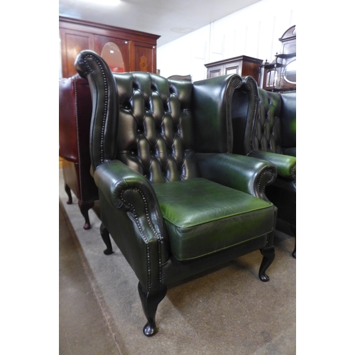 25 - A green leather Chesterfield wingback armchairs