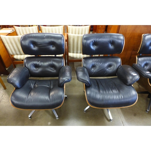 90 - A pair of Charles & Ray Eames style black leather, simulated rosewood and chrome revolving lounge ch... 