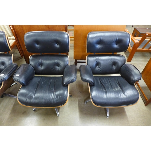 91 - A pair of Charles & Ray Eames style black leather, simulated rosewood and chrome revolving lounge ch... 