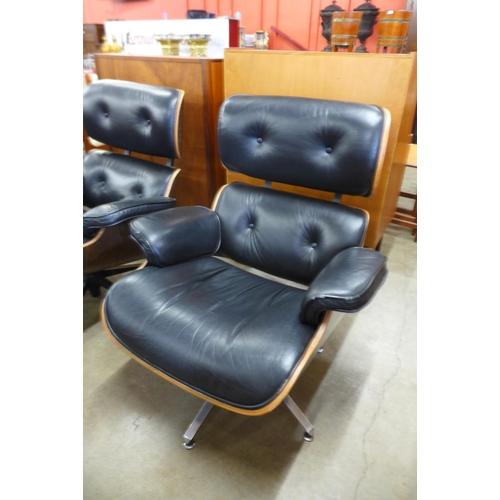 91 - A pair of Charles & Ray Eames style black leather, simulated rosewood and chrome revolving lounge ch... 