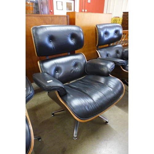 91 - A pair of Charles & Ray Eames style black leather, simulated rosewood and chrome revolving lounge ch... 