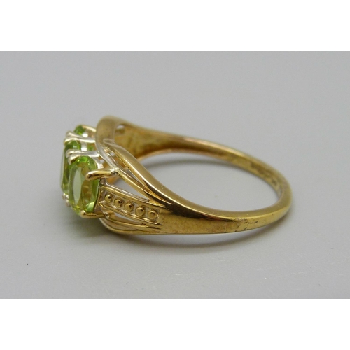 1009 - A silver-gilt peridot trilogy ring, O