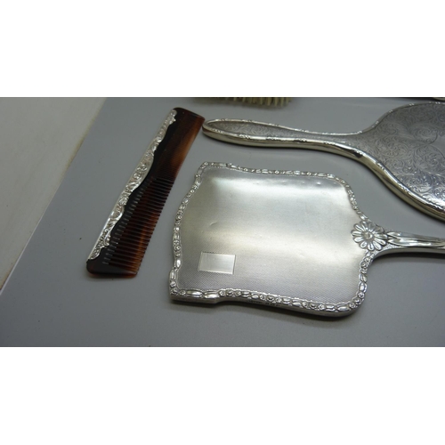 852 - A silver backed hand mirror with two matching brushes, one other silver backed hand mirror and a sil... 