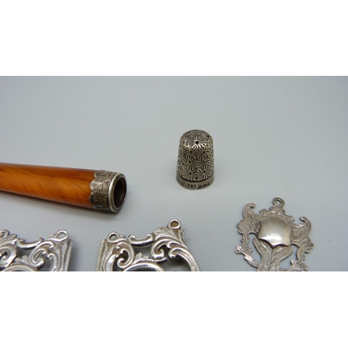 973 - A silver buckle, an amber cheroot holder, four silver fobs, badge and thimble, 73g