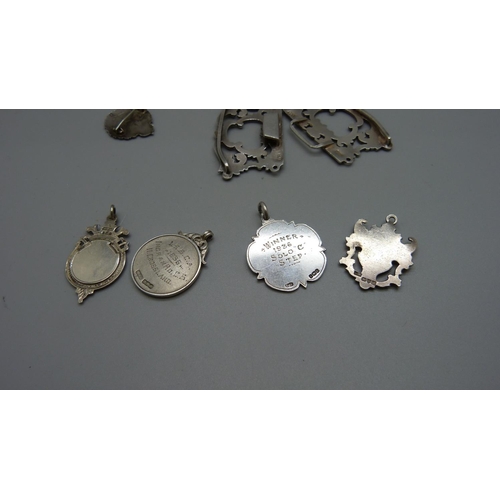 973 - A silver buckle, an amber cheroot holder, four silver fobs, badge and thimble, 73g