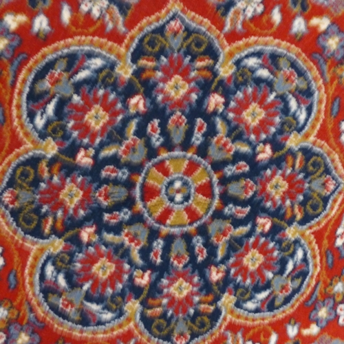 1567 - A floral patterned red ground Turkish woolen rug, 120x170cm