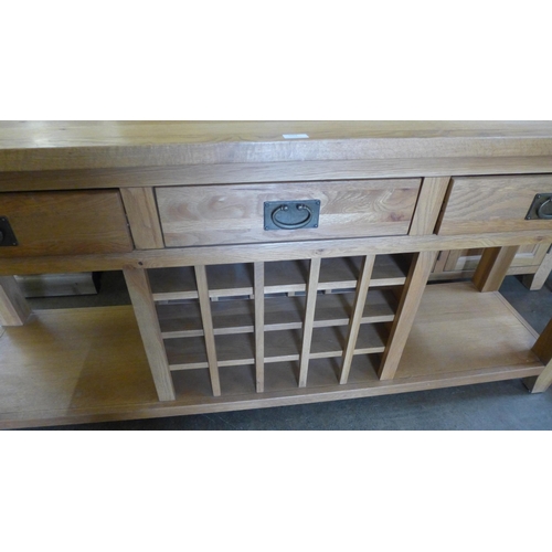 1569 - An oak three drawer wine sideboard