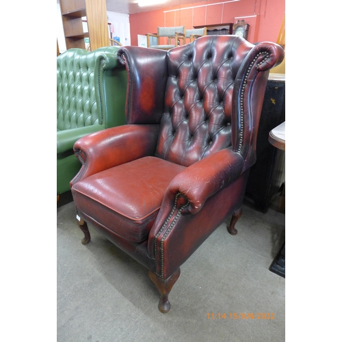 136 - An oxblood red leather Chesterfield wingback armchair