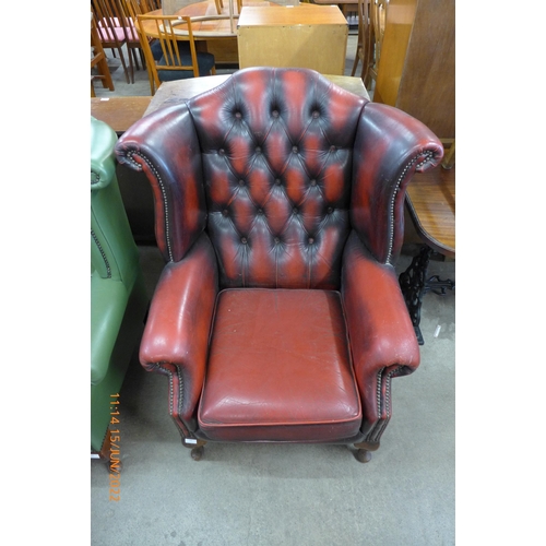 136 - An oxblood red leather Chesterfield wingback armchair