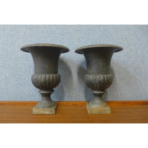 369 - A pair of miniature cast iron campana shaped urns