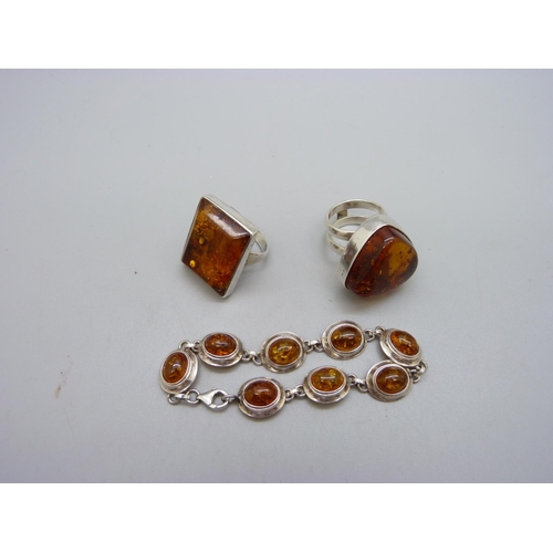 1070 - A silver and amber bracelet and two amber set rings, both Q