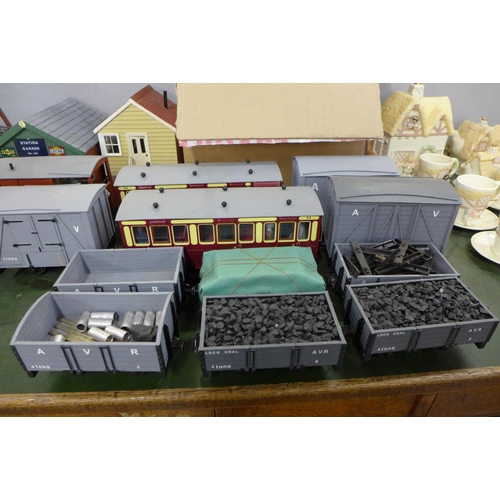 782 - A large collection of garden model rail, carriages, wagons, buildings, scenery and track with a fold... 