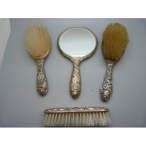 876 - A silver backed hand mirror and three brushes