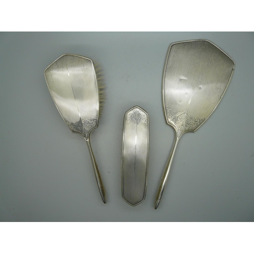 881 - A silver backed hand mirror and two brush set, Birmingham 1963