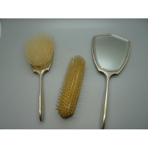 881 - A silver backed hand mirror and two brush set, Birmingham 1963