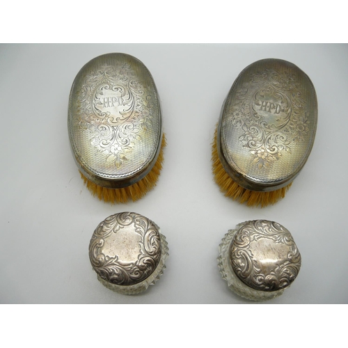 891 - A pair of silver backed brushes and a pair of silver topped glass jars