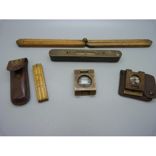 920 - A folding ruler, a Coopers' gauge, two brass folding magnifying glasses and a spirit level