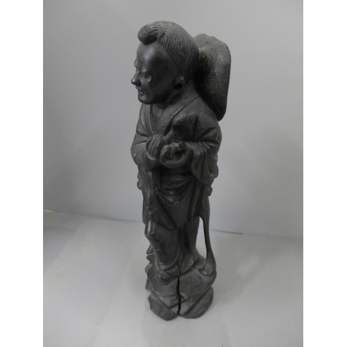 793 - A carved wooden figure of a Chinese man, ebonised wood with metal inlay decoration, 32cm