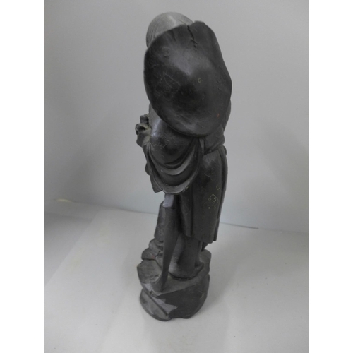 793 - A carved wooden figure of a Chinese man, ebonised wood with metal inlay decoration, 32cm