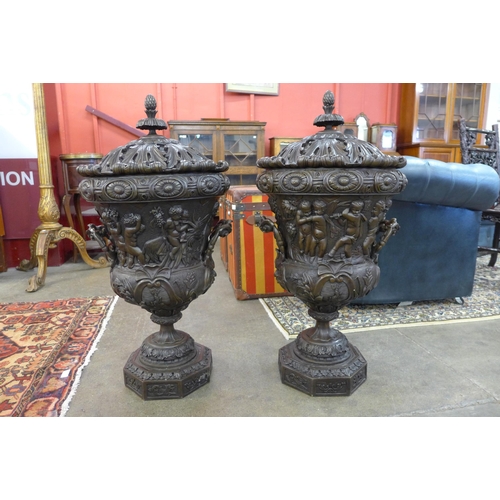 13 - A pair of large Italian style bronze campana shaped urns and covers, cast with Bacchanalian cherubs