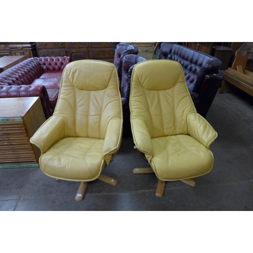 98 - A pair of beech and leather swivel lounge chairs