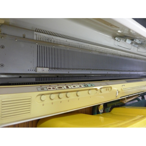 2361 - Empisal  Knitmaster model 550 electronic knitting machine with 2 bags of wool, table, patterns, wool... 