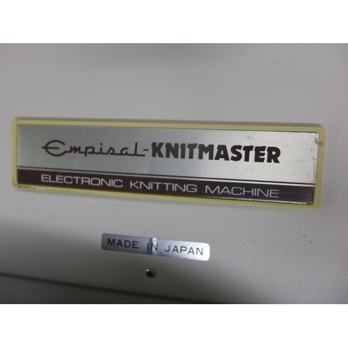 2361 - Empisal  Knitmaster model 550 electronic knitting machine with 2 bags of wool, table, patterns, wool... 